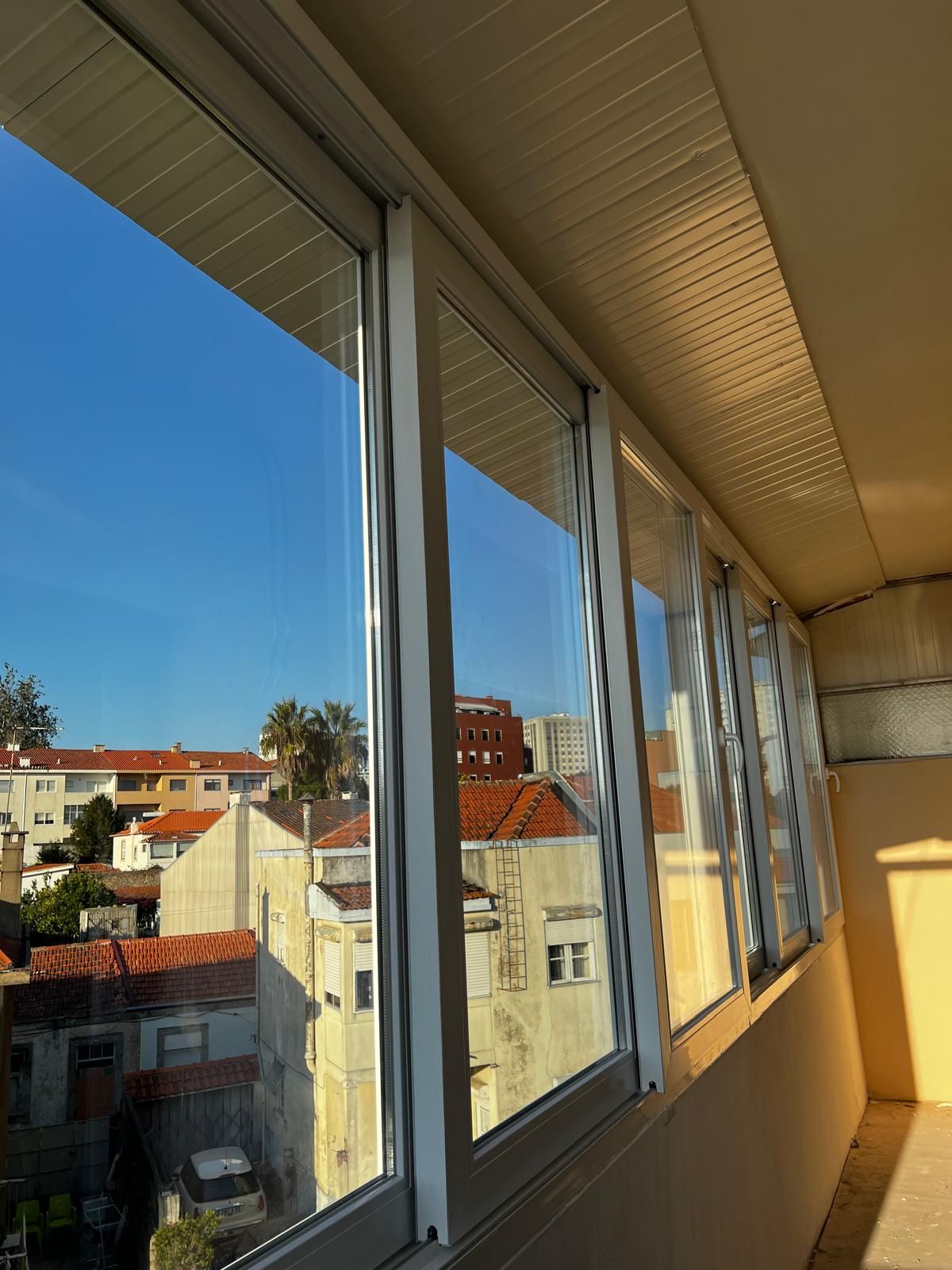 Caixilharia PVC instalada — varanda envidraçada com vista da cidade